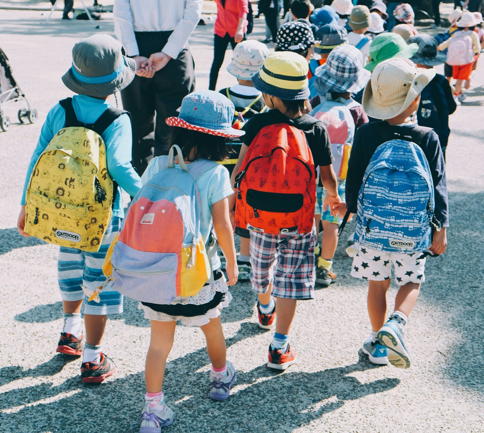 school aged children walking across a parking lot after arriving at school